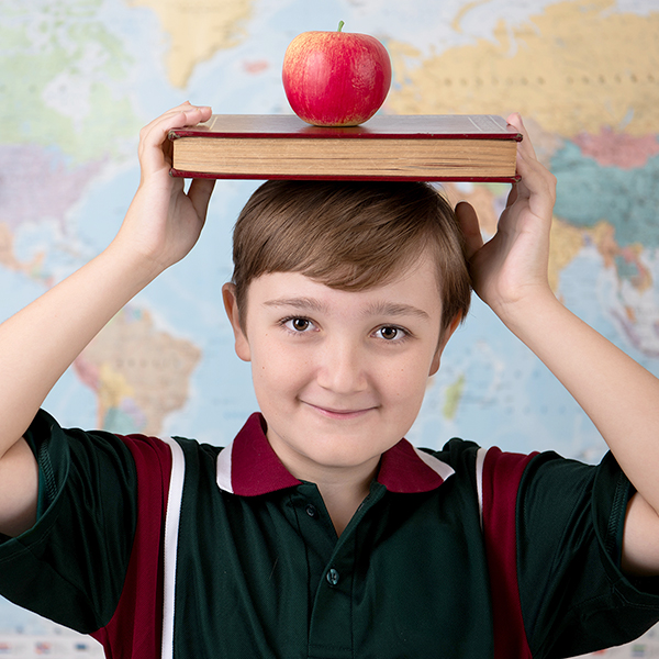 School Boy posing for photo with book and apple